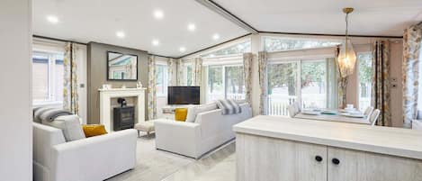A modern living room with a sofa, a TV, and a dining area with a table and chairs.