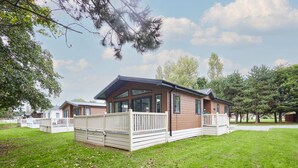 Una casa móvil moderna con terraza, rodeada de césped y árboles.