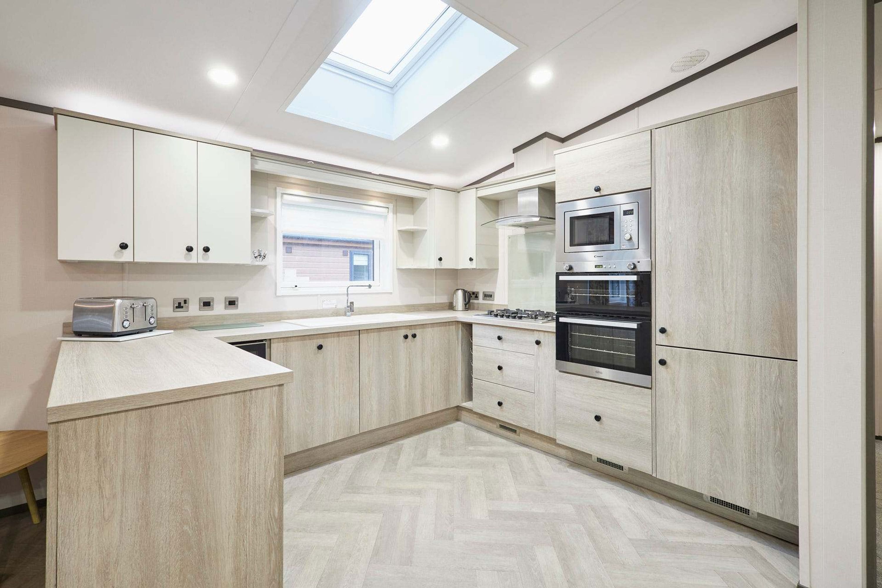 A modern kitchen with light wood cabinetry, a built-in microwave, and a gas stove.