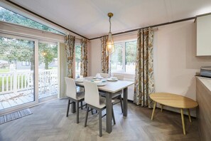 A dining area with a table and chairs, a bench, and a view of the outdoors. - Host Stay Brackencroft Lodge (York)