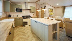 Una cocina moderna con una isla central, electrodomésticos integrados y un rincón comedor con sofá.