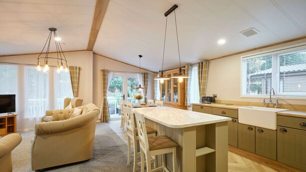 Amplia sala de estar con sofá, sillas, una cocina con una isla grande y un comedor.