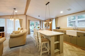 A spacious living area with a sofa, chairs, a kitchen with a large island, and a dining area. - Host Stay Foxglove Lodge (York)