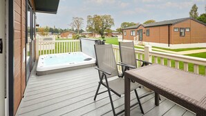 A deck with a hot tub, chairs, and a table. - Host Stay Woodpecker Lodge (York)