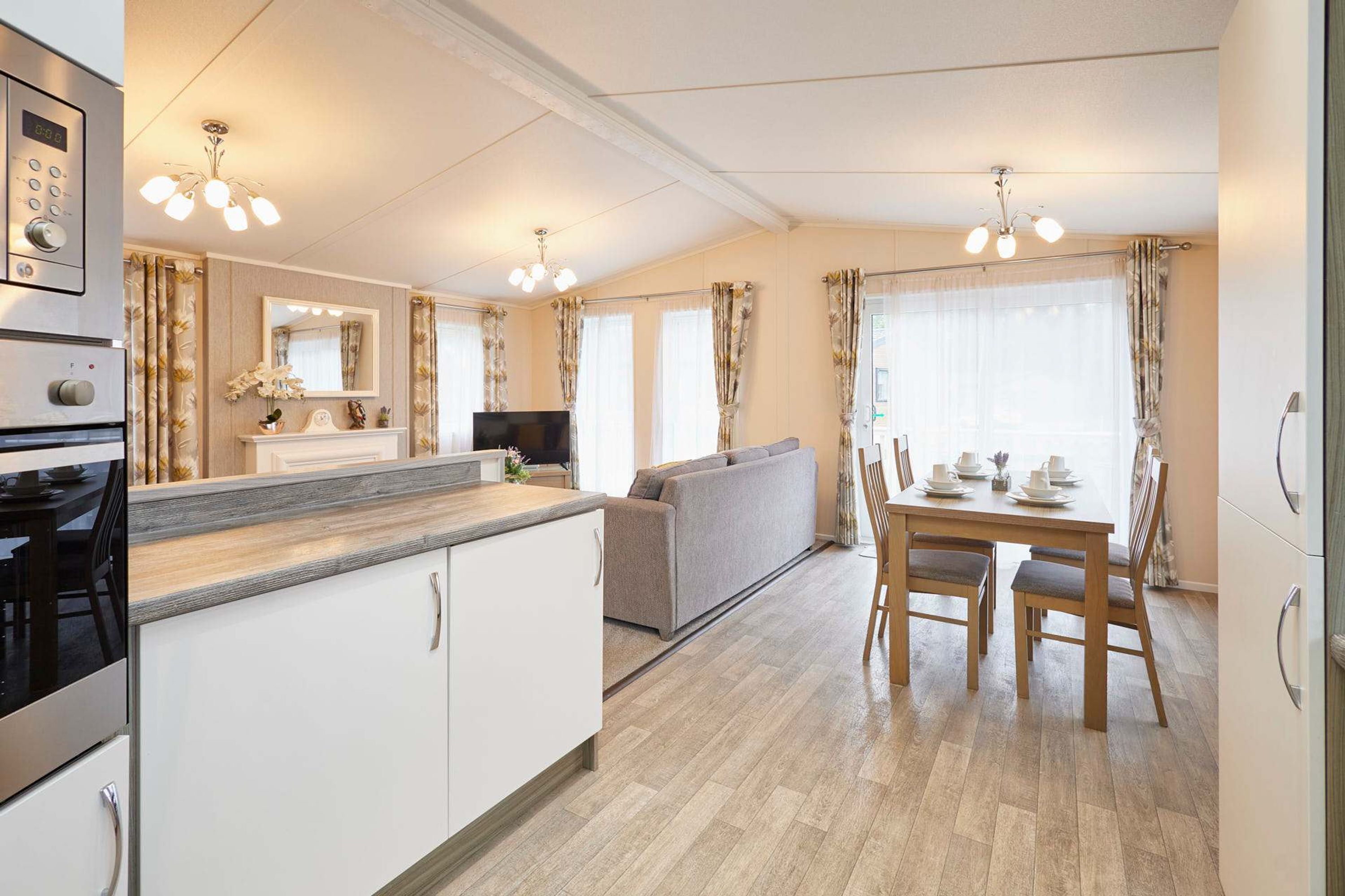 A modern kitchen with a built-in oven, a dining area with a table and chairs, and a sofa in the living area.