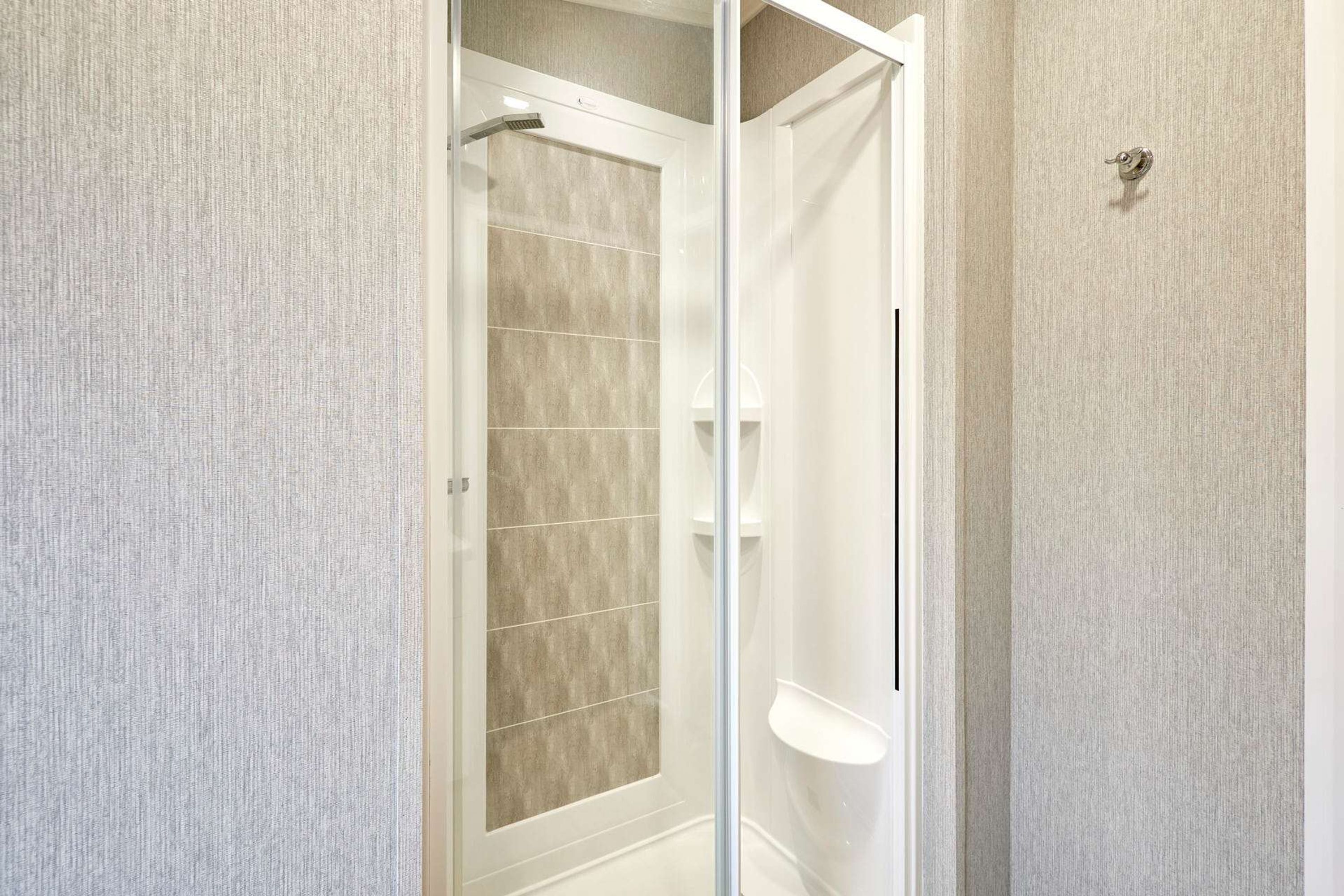 A bathroom with a glass shower enclosure, a white sink, and a towel rack.