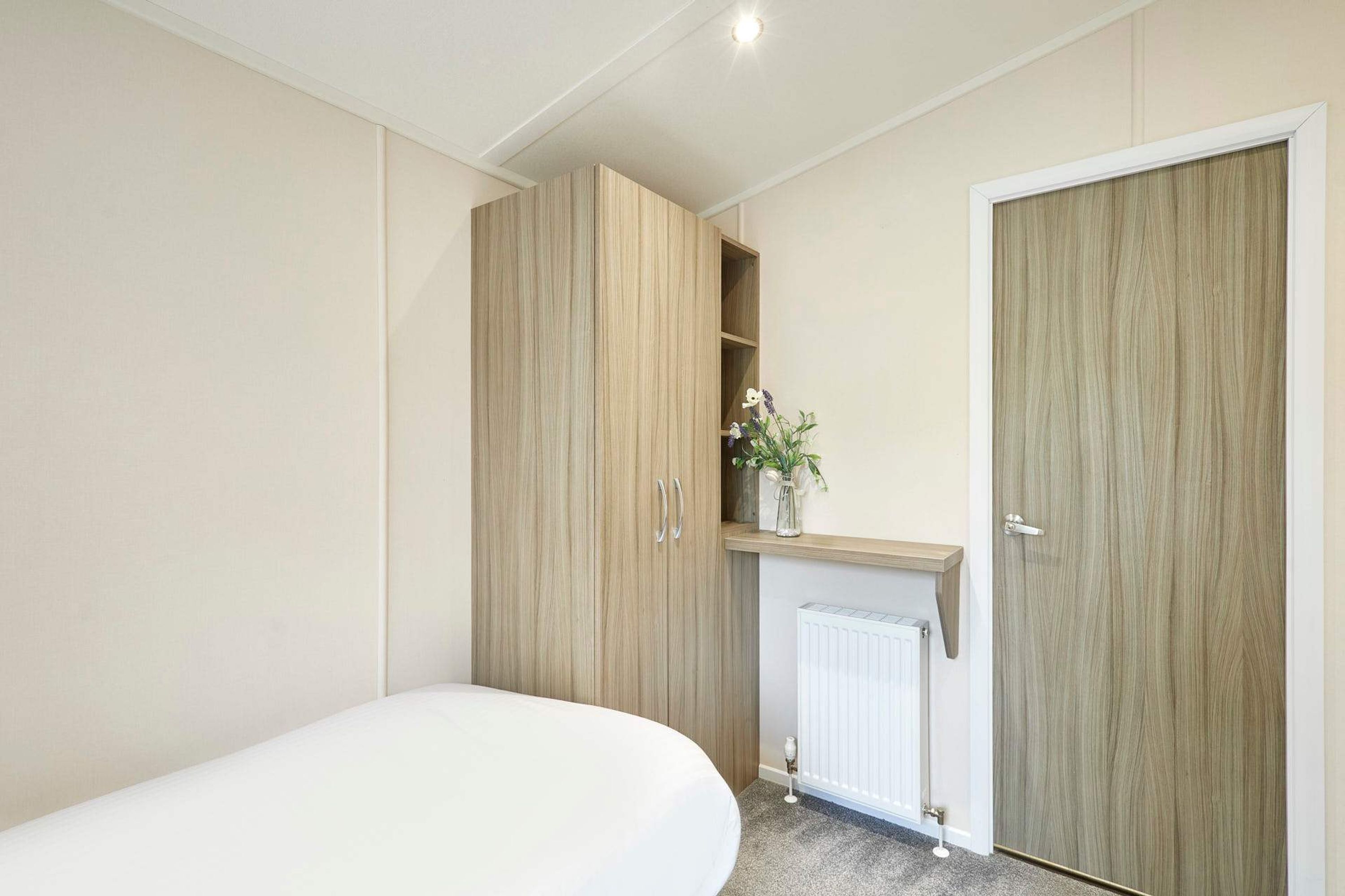 A bedroom with a bed, wooden wardrobe, and a radiator.