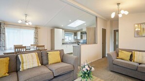 A modern living room with sofas, a coffee table, and a dining area. - Host Stay Woodpecker Lodge (York)