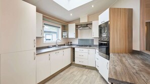A modern kitchen with white cabinets, a skylight, and a wooden countertop. - Host Stay Woodpecker Lodge (York)