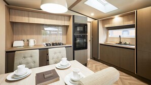 A compact kitchen with a dining area, featuring a microwave, oven, and a small window. - Host Stay Field View Lodge (York)