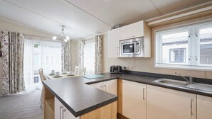A compact kitchen with a microwave, sink, and wooden counter. - Host Stay Bluebell Lodge (York)