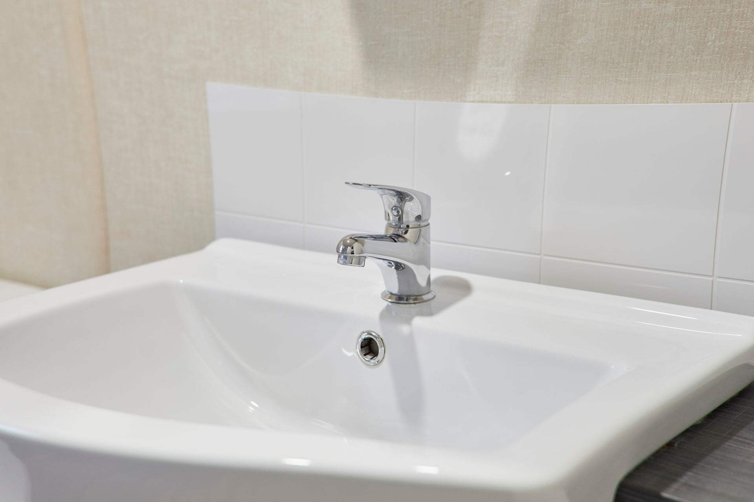 Een wit badkamermeubel met een chroom kraan en een betegelde muur.