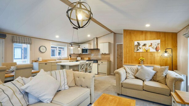 A modern living room with a sofa, a coffee table, and a kitchen area in the background. - Host Stay Water s Edge Lodge (York)