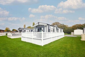 A mobile home with a white exterior, a fenced deck, and a large window. - Host Stay Lakeview Winter (York)