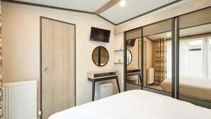 Una camera d'albergo con un letto, una televisione a muro, uno specchio e un termosifone.
