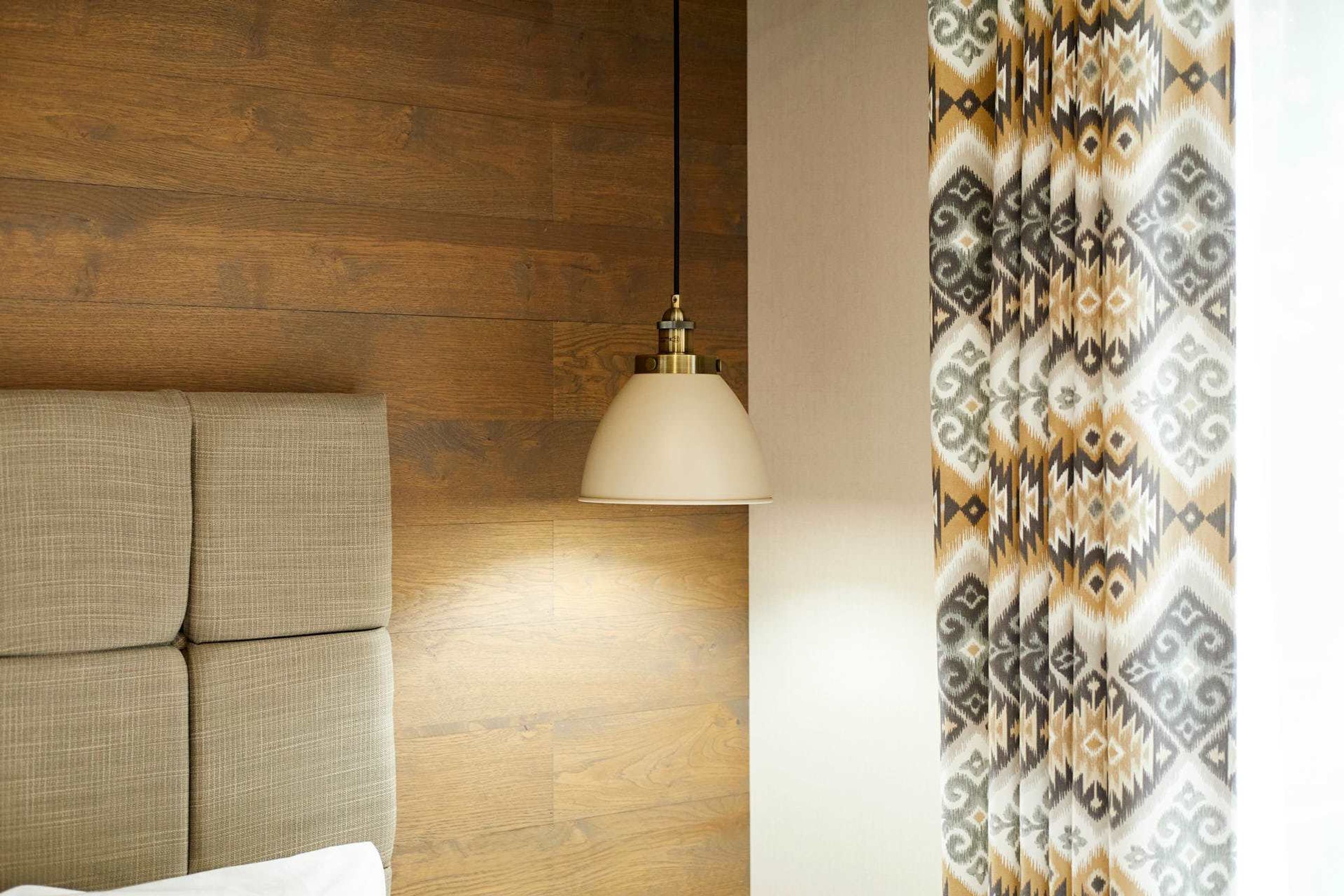 A room with a wooden wall, a sofa, and a patterned curtain.