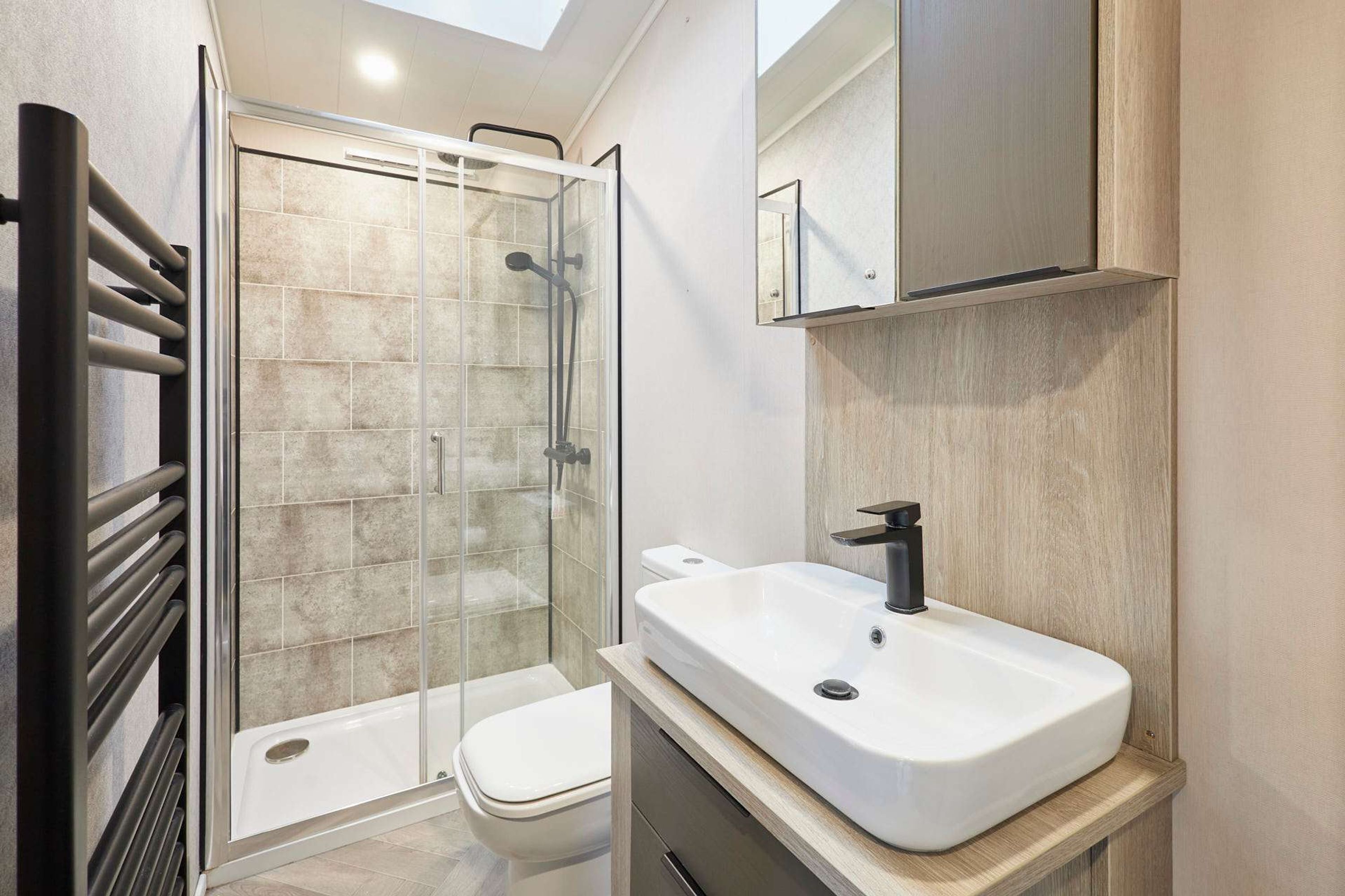 A modern bathroom with a glass shower enclosure, a white sink, and a toilet.