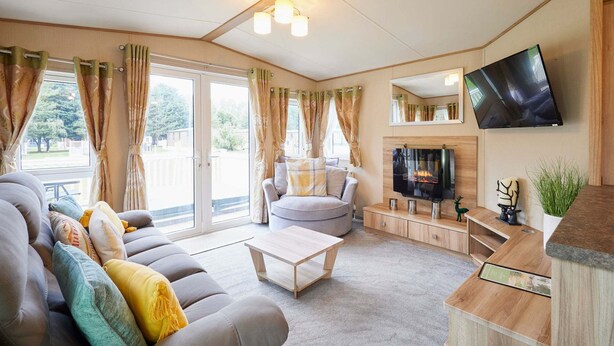 A modern living room with a sofa, a coffee table, a TV, and a fireplace. - Host Stay Brooksbank Lodge (York)