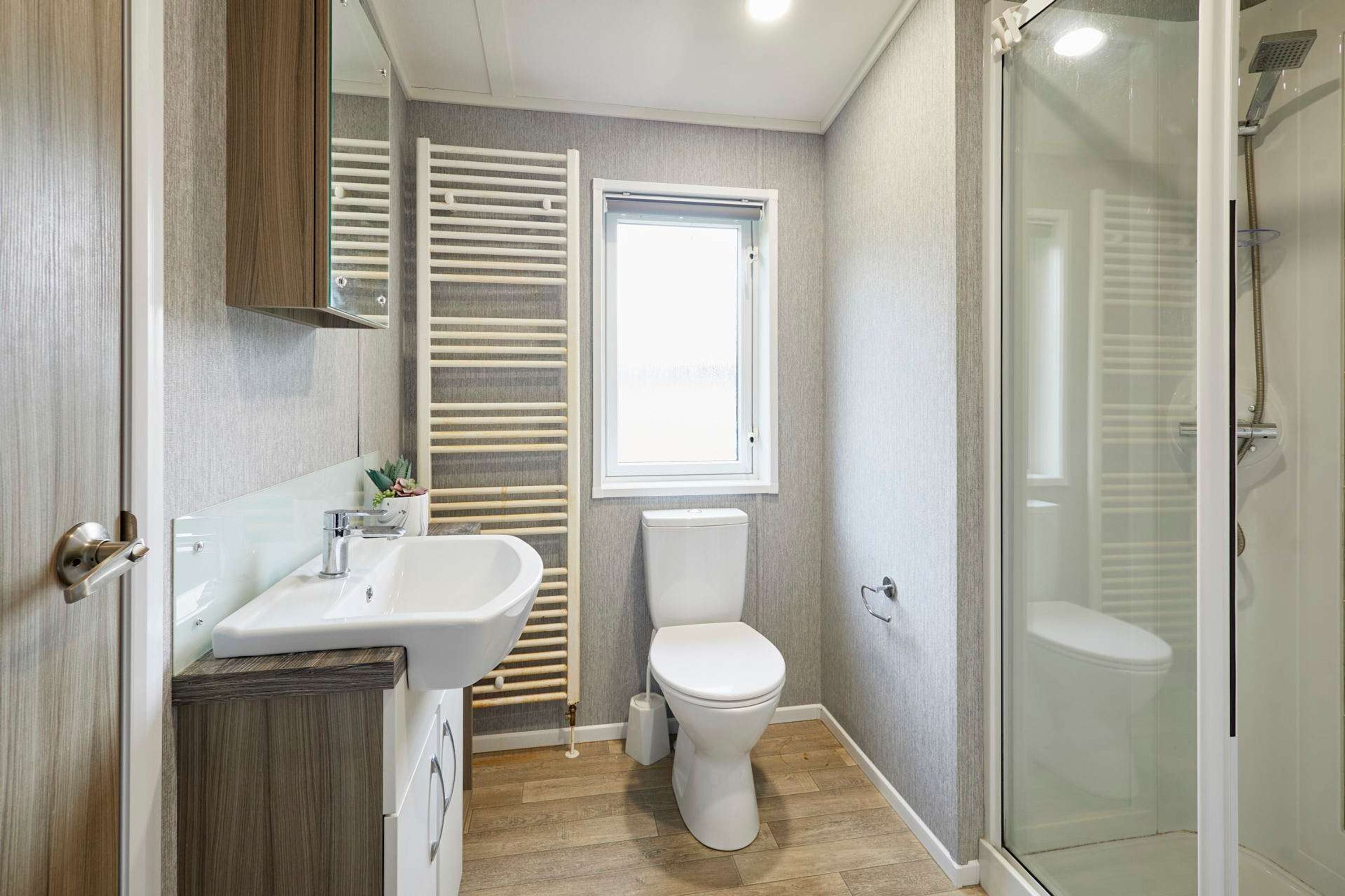 A bathroom with a sink, toilet, and glass shower enclosure.