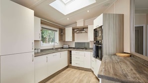 Una cocina moderna con armarios blancos, encimera de madera y tragaluz.