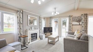 Una sala de estar con chimenea, sofá, televisor y un ventanal grande.