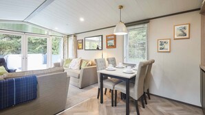 A modern living room with a sofa, a dining table with chairs, and artwork on the walls. - Host Stay 23 Sandy Lane (York)
