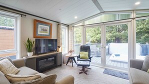 A cozy living room with a fireplace, comfortable seating, a television, and a view of the outdoors. - Host Stay 23 Sandy Lane (York)