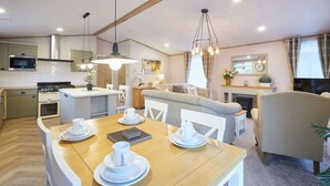 A modern kitchen with a microwave, stove, and dining area with white chairs and a wooden table set for a meal. - Host Stay Barakah Lodge (York)