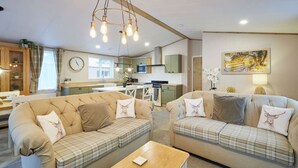 A cozy living room with two sofas and a coffee table, a kitchen in the background, and a dining area. - Host Stay Barakah Lodge (York)