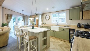 A modern kitchen with a central island, green cabinets, and a large window. - Host Stay Barakah Lodge (York)