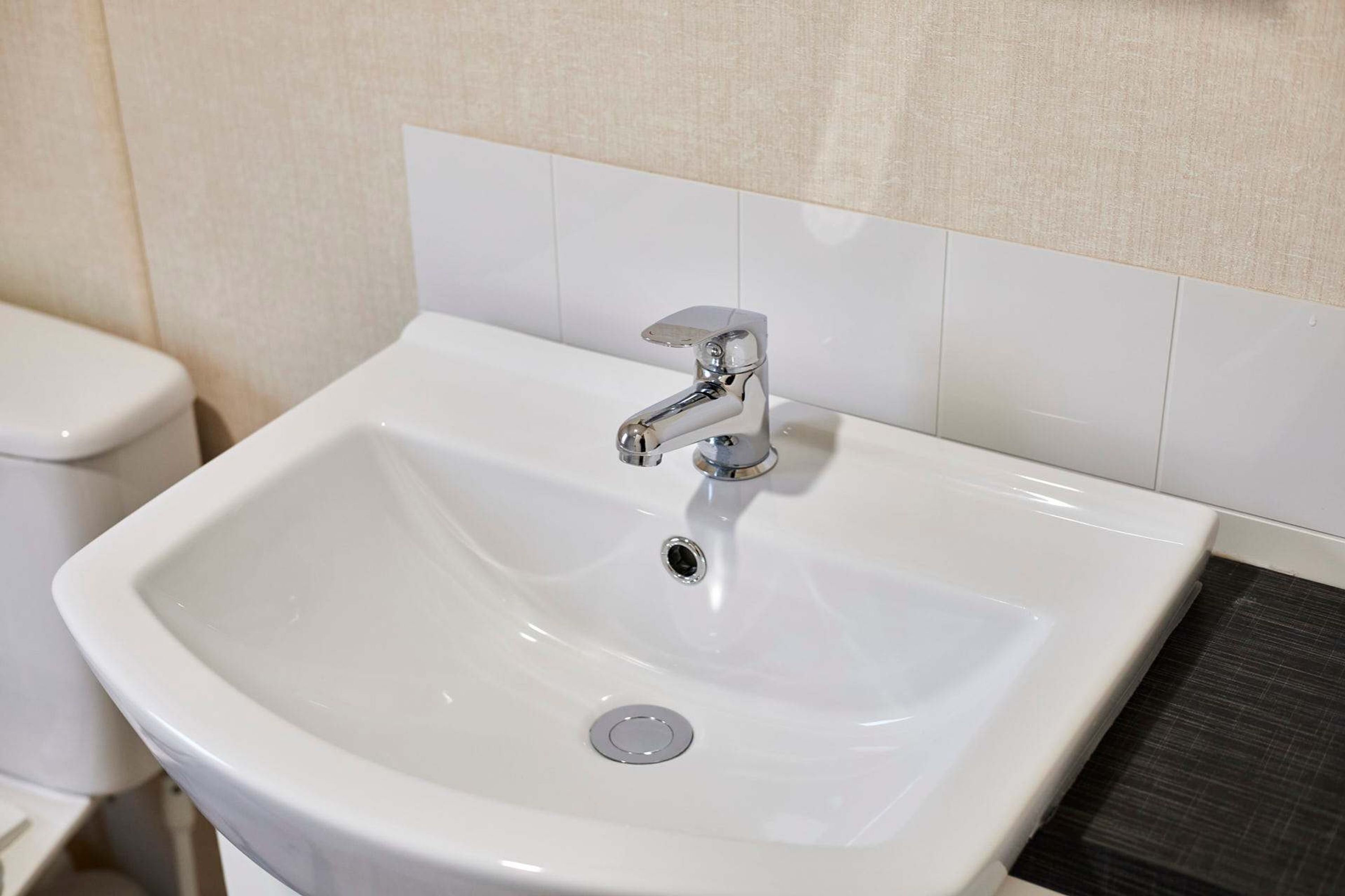 A white bathroom sink with a chrome faucet and a single drain.