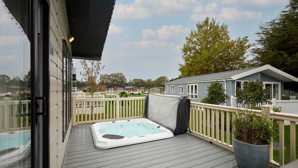 A deck with a hot tub, a potted plant, and a view of a residential area. - Host Stay Primrose Lodge (York)