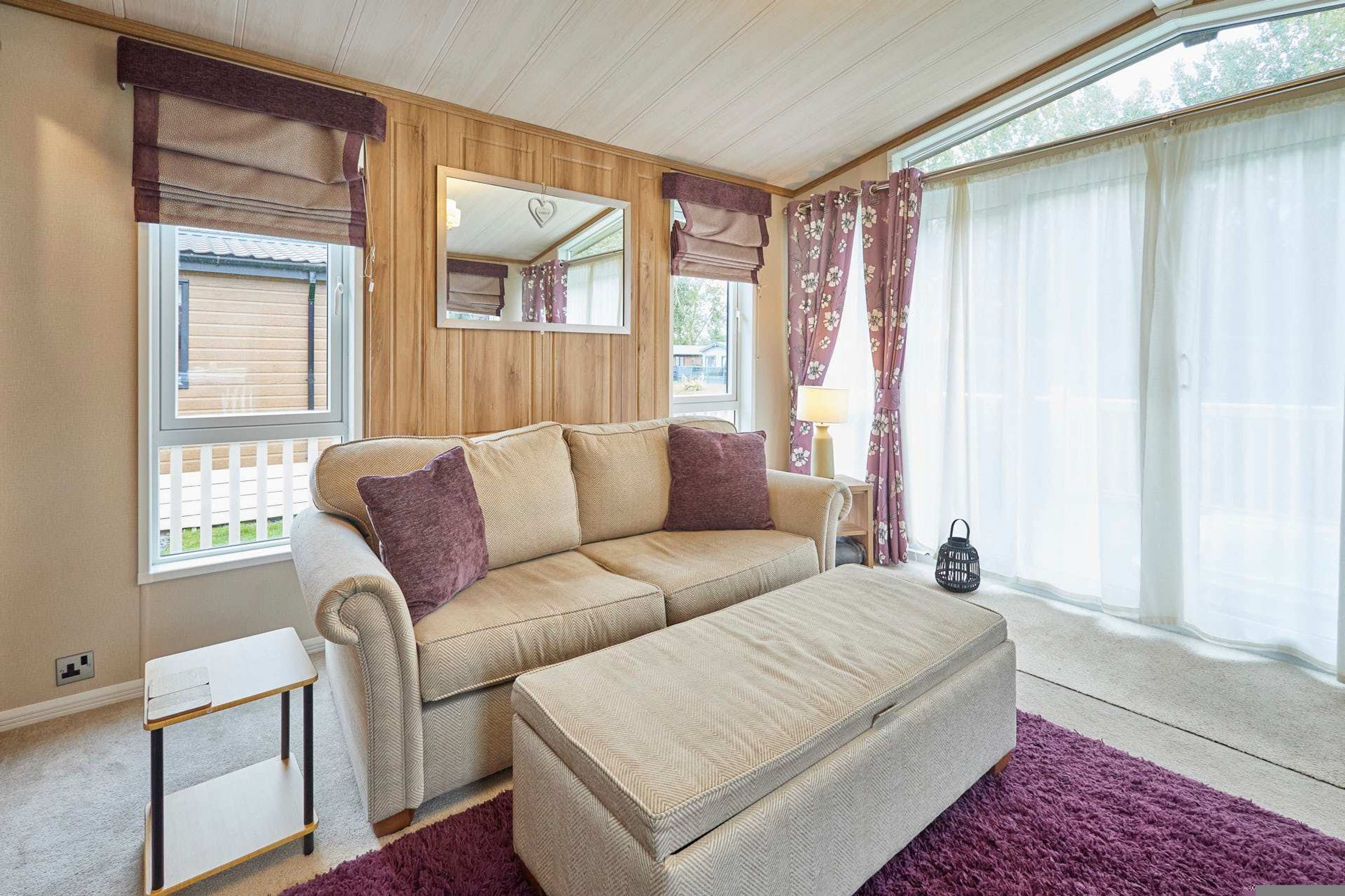 A cozy living room with a sofa, ottoman, and a small table.