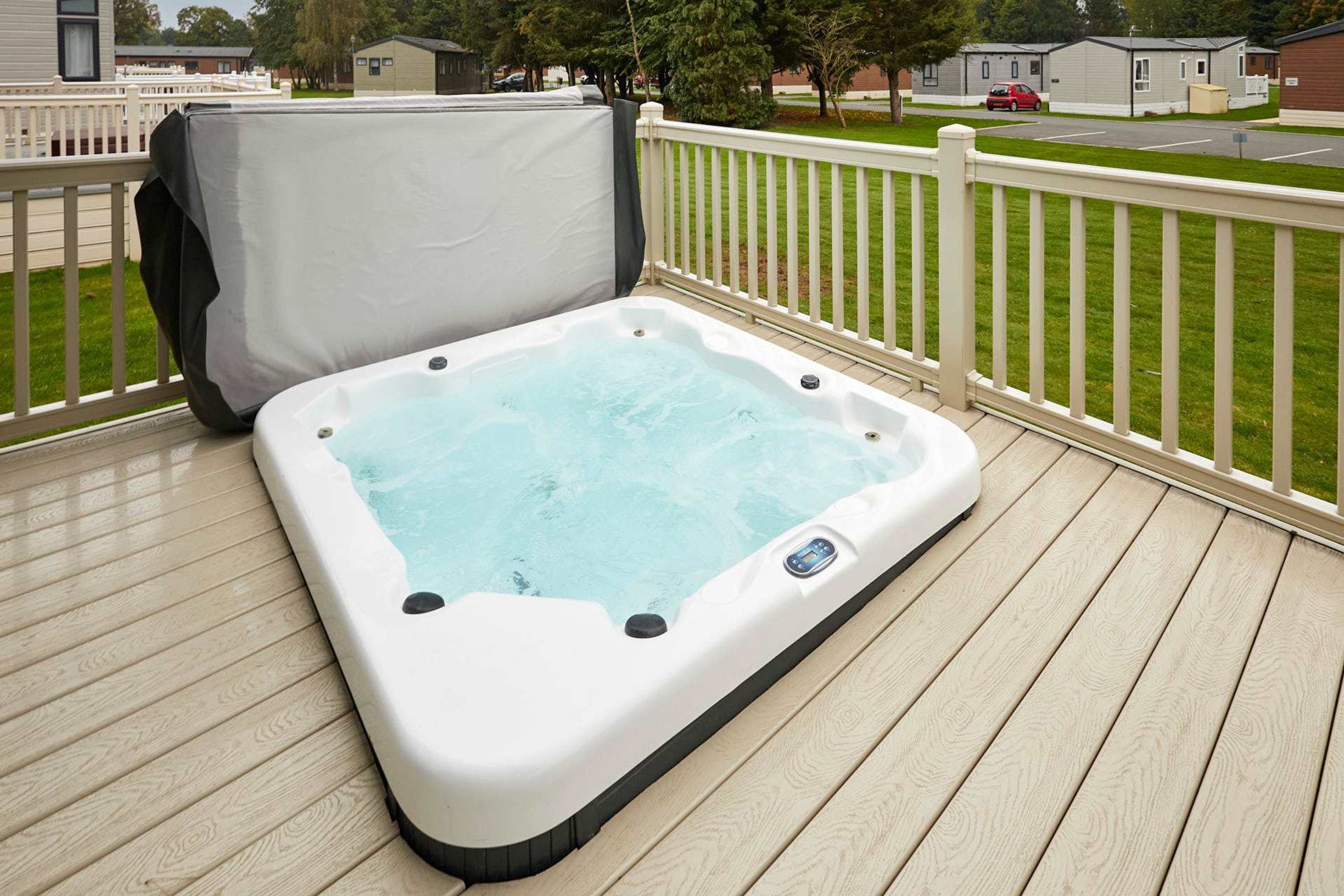 Un bain à remous sur une terrasse en bois avec une balustrade blanche.