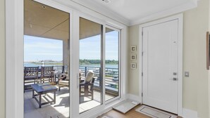 Une pièce dotée d’une porte-fenêtre coulissante donnant sur un balcon aménagé avec du mobilier d’extérieur et offrant une vue sur un port de plaisance.