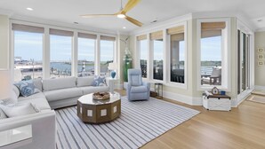 Un salon spacieux doté d’une grande fenêtre, d’un ventilateur de plafond et offrant une vue sur le bord de l’eau.