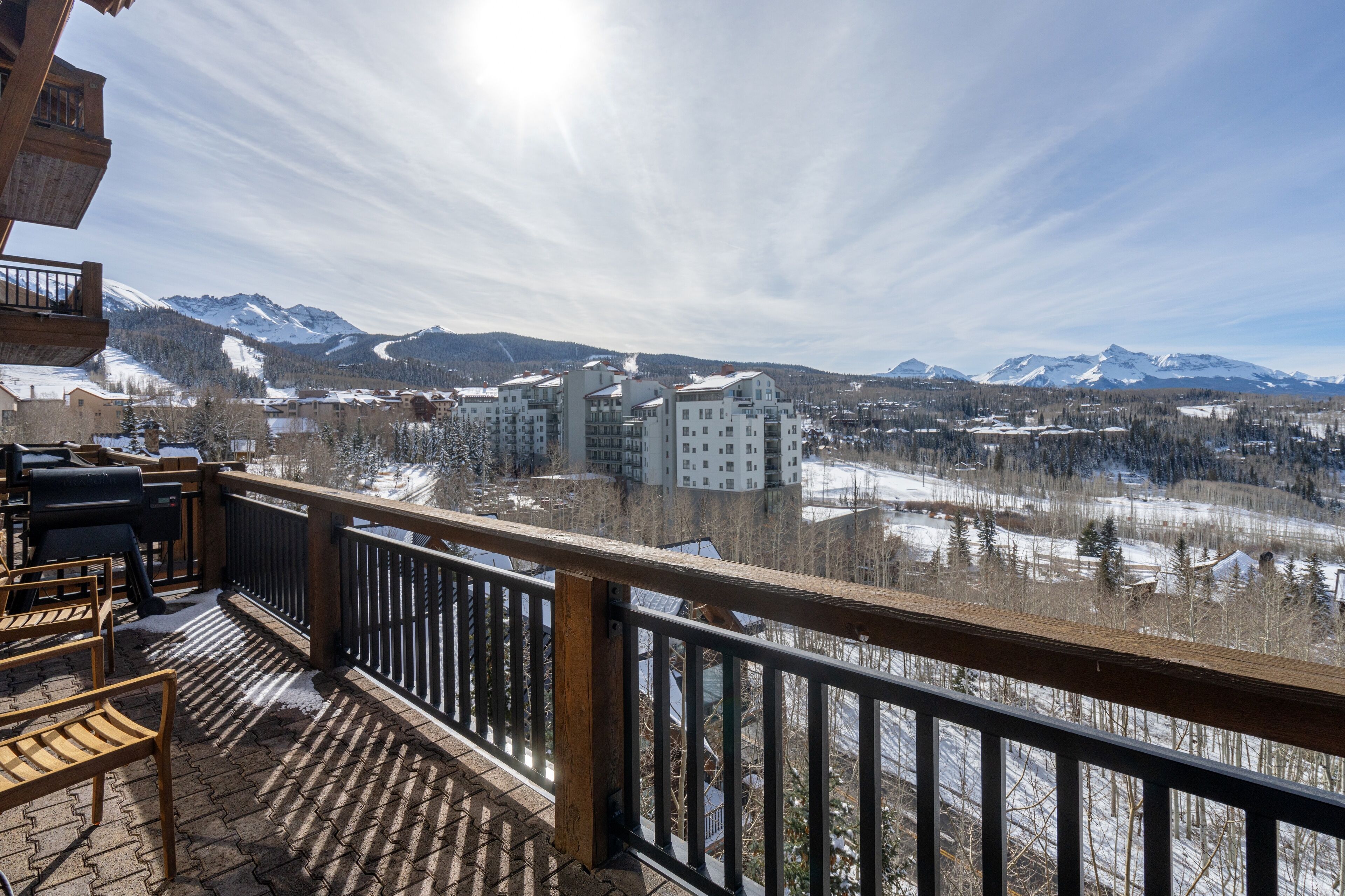 Ein Balkon mit Holzgeländern mit Blick auf eine verschneite Landschaft und Berge in der Ferne.