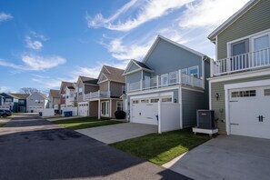 A row of single-family homes with attached garages, a clear sky, and a well-maintained lawn. - Spacious 4 bed, 3.5 bath townhome located in Ocean View Beach Club; community pool, fitness center, shuttle, playground, sauna, Free WIFI (Ocean View)