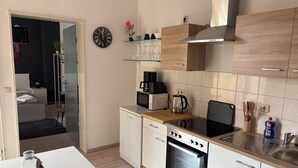 Cocina moderna con armarios blancos, horno empotrado, microondas y cafetera.