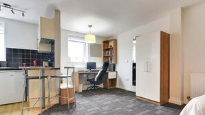 Un apartamento moderno con cocina, comedor, espacio de trabajo y un dormitorio.