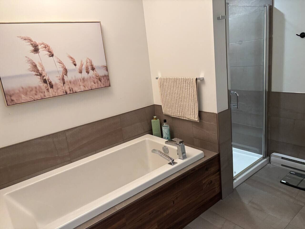 A modern bathroom with a large bathtub, a glass shower enclosure, and a wall-mounted towel rack.