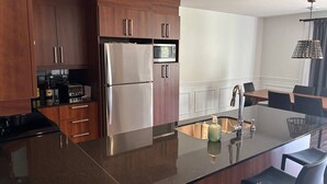 Una cucina moderna con elettrodomestici in acciaio inossidabile, mobili in legno e un'isola centrale con sgabelli da bar.