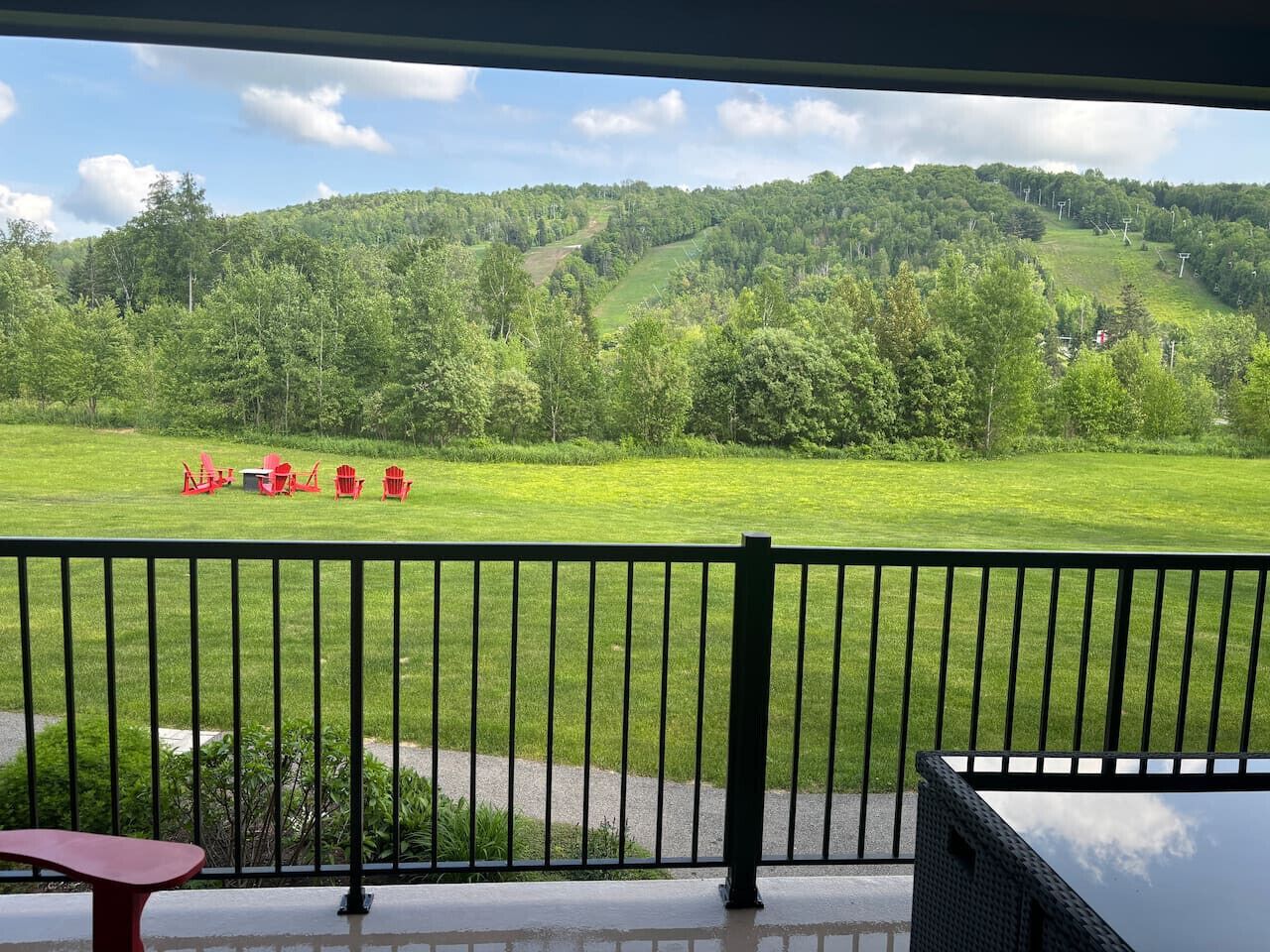 Een balkon met uitzicht op een groen veld en heuvels.