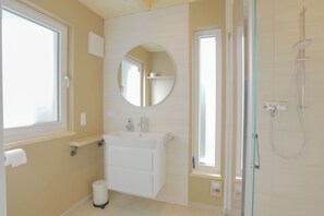 A bathroom with a sink, mirror, toilet, and shower. - "Zum Hafen 21" Vacation Home in Zislow, nestled between the forest and the lake (Zislow)
