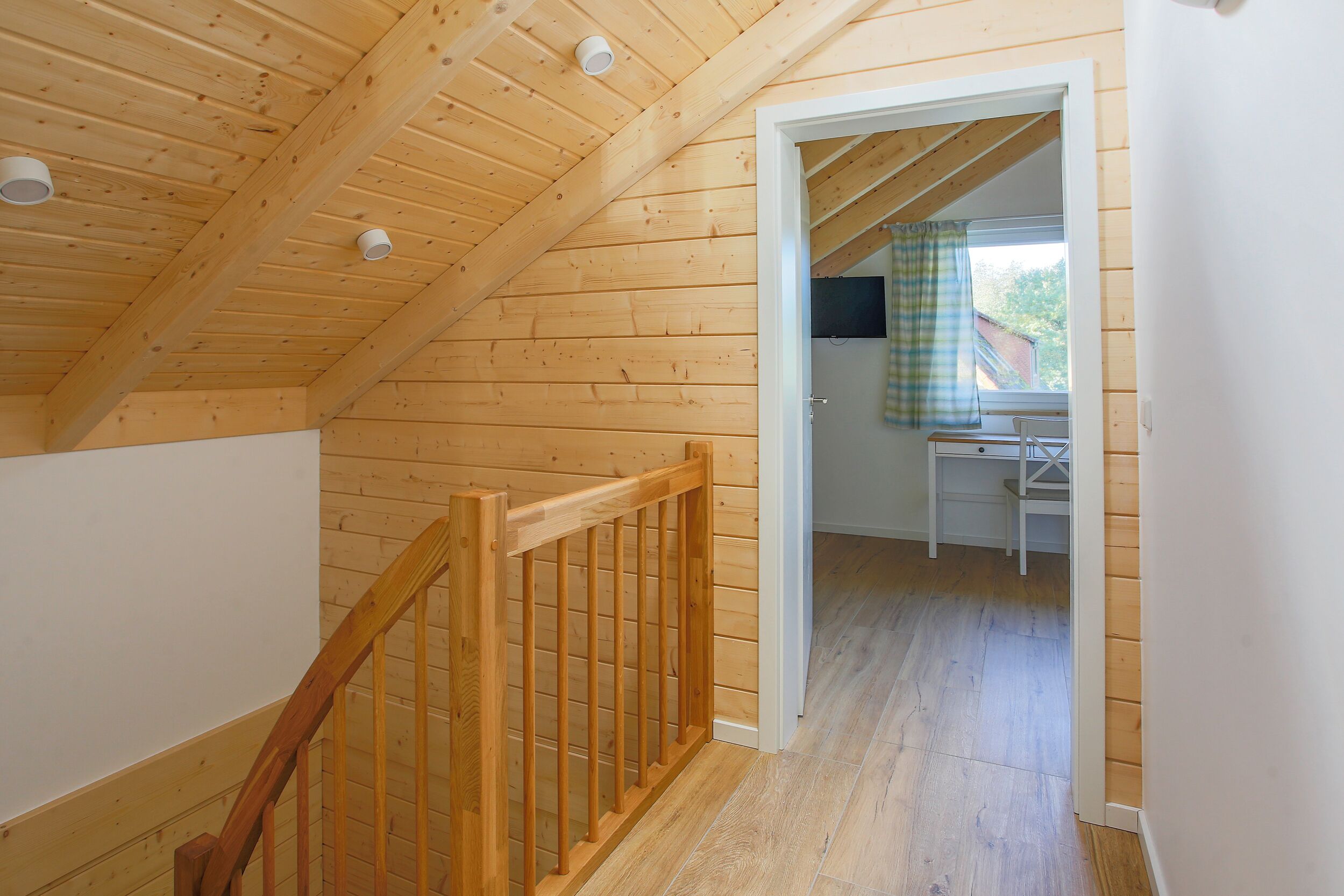 Un intérieur en bois avec un escalier menant à une pièce dotée d’une fenêtre et d’une table.