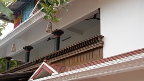 A multi-story building with traditional architectural elements, including a balcony with ornate railings and a colorful mural on the exterior wall. -  Kulture KonnectT North Cliff" (Varkala)