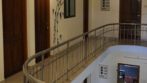 A multi-level interior with wooden doors, a metal railing, and a wall-mounted artwork. -  Kulture KonnectT North Cliff" (Varkala)