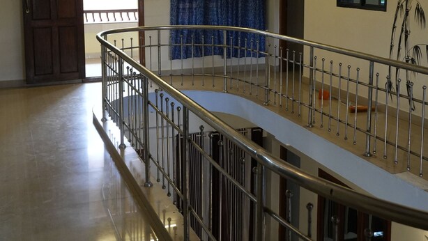 A spacious room with a polished floor, a metal railing, a large window with a view, and a door leading outside. -  Kulture KonnectT North Cliff" (Varkala)