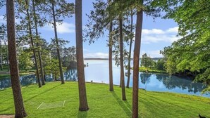 En välskött gräsmatta med ett trädäck och utsikt över en sjö.