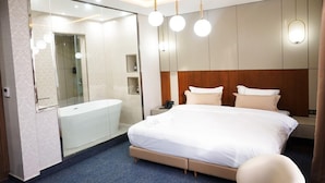 Una habitación de hotel moderna con una cama grande, ducha integrada y tocador con espejo.